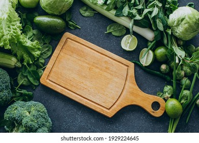 Green vegetables and breadboard on table background