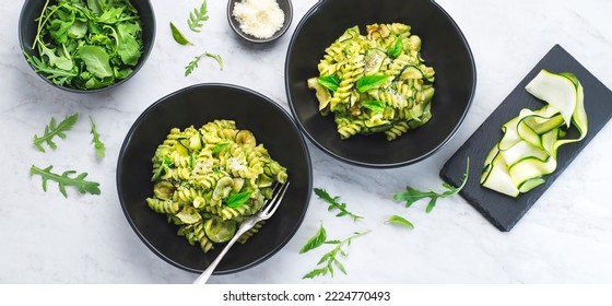 Green Vegetarian Fusilli Pasta With Zucchini Pesto And Herbs On A White Marble Background In A Black Bowl. Healthy And Economical Recipes For The Whole Family, Italian Pasta. Internet Banner