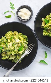 Green Vegetarian Fusilli Pasta With Zucchini Pesto And Herbs On A White Marble Background In A Black Bowl. Healthy And Economical Recipes For The Whole Family, Italian Pasta,top View