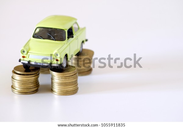 Green vintage collectible tiny car, miniature\
standing on stacks of golden coins. Transportation market, used\
retail and motor spares shop, automobile industry trend, car\
rental, and saving\
concept.