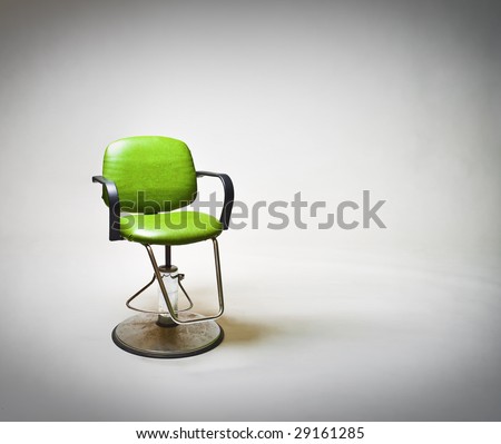 Green vintage vinyl covered barbershop or beauty salon chair against large white backdrop. Lots of copy space to right.