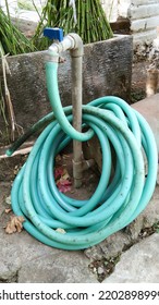 Green Water Hose Attached To The Water Faucet