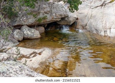 A green waterpool of river Pitrisconi surrounded by rocks in Sardinia