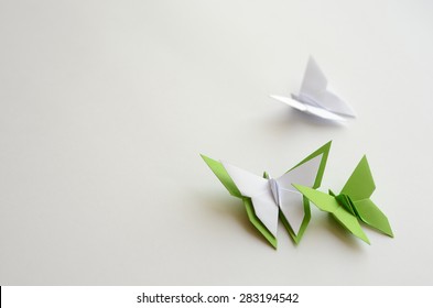 Green and white origami butterflies on white background