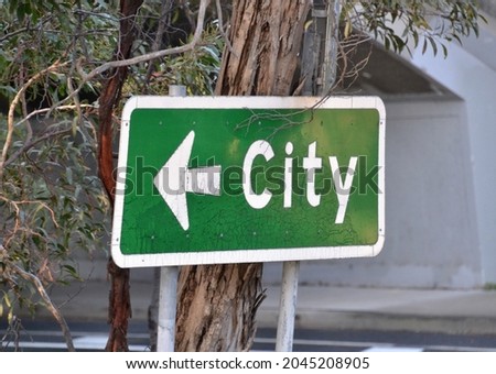 Green and white road sign with an arrow indicating the direction to the city CBD in Melbourne 