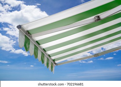 Green And White Striped Awning Against Blue Sky