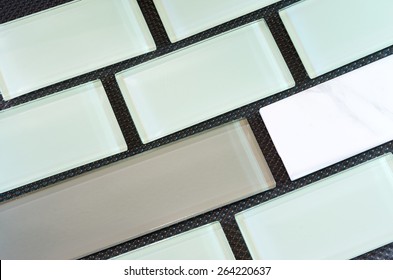 Green White And Taupe Colored Glass And Porcelain Subway Tile Or Backsplash Against Black Background Arranged In Rows 