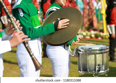 Green And White Uniform Cymbals Player In Marching Band With Drumer And Clarinet Player.