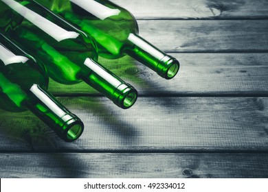 Green wine bottles on black grunge wooden table background.
