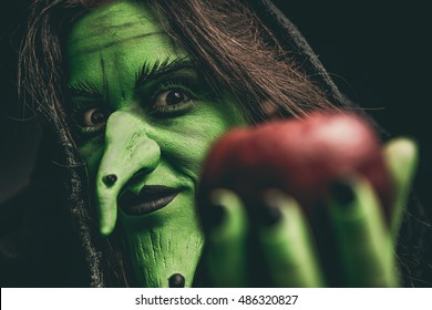 Green Witch Holding An Apple In Her Hand. Shallow Depth Of Field.