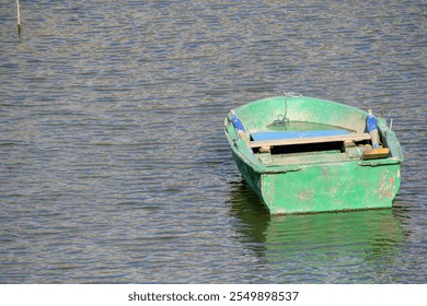 Green wooden boat floating on calm water. A small green wooden boat floats peacefully on calm waters, with sunlight highlighting its aged surface and serene surroundings. - Powered by Shutterstock