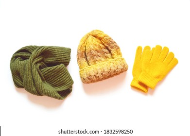 Green woolen scarf, yellow knitted hat and gloves isolated on a white background. Flat lay autumn and winter clothes. Bright accessories for stylish outfit