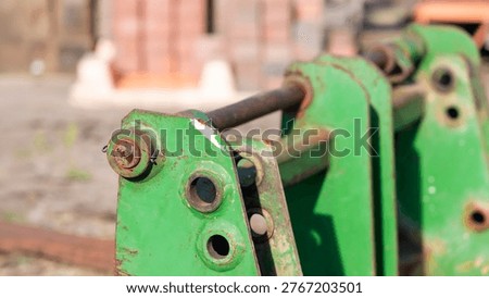 Green worn excavator quick coupler attachment showing rust and heavy use at construction site.