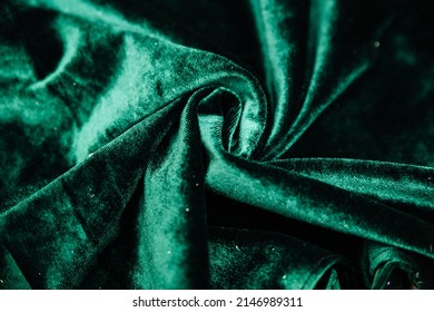 A Green, Wrinkled Fabric Lies In Folds On A Draped Table. Emerald Velvet. Texture