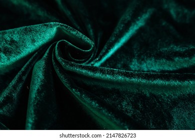 A Green, Wrinkled Fabric Lies In Folds On A Draped Table. Emerald Velvet. Texture