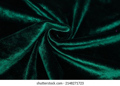 A Green, Wrinkled Fabric Lies In Folds On A Draped Table. Emerald Velvet. Texture