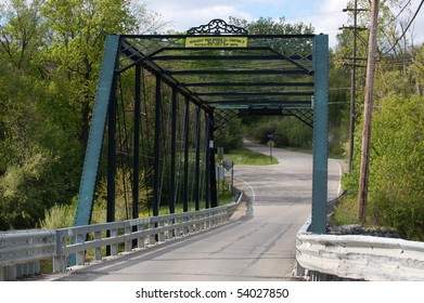 Green wrought iron bridge over river, from road