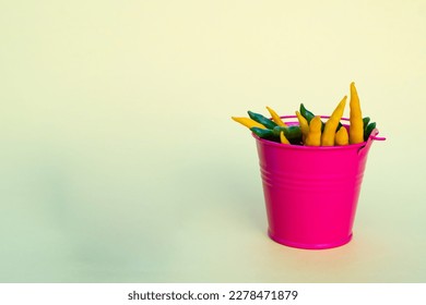 Green and yellow chili peppers in a pink bucket with copy space. The concept of agriculture and advertising of organic products - Shutterstock ID 2278471879