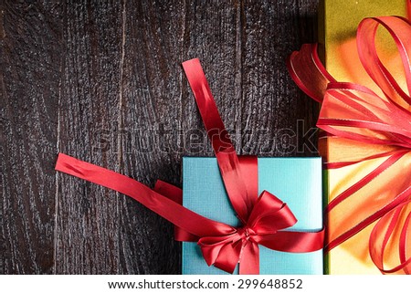 green and yellow gift box red bow on wood table, top view