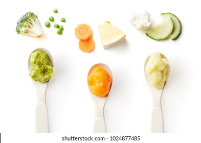 Green, yellow and orange baby puree in baby spoon isolated on white background, top view
