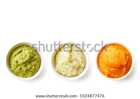 Green, yellow and orange baby puree in bowl isolated on white background, top view