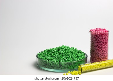 Green, yellow and pink  granules of polypropylene or polyamide on a white background. Plastics and polymers industry. Copy space. Glass petri dish, flask, volumetric glassware, test tube. 