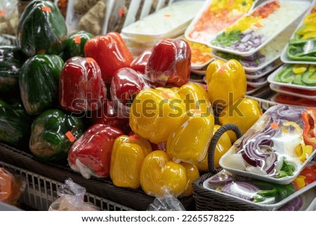 green, yellow, and red bell peppers wrapped in plastic on display in baskets at the Municipal Market in Atlanta Georgia USA