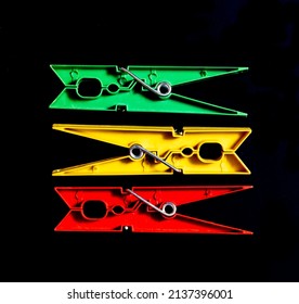 Green, yellow and red clothing pegs, isolated on black.