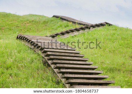 A green Zig Zag stairs uphill. Concept growth on grass