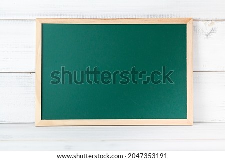 Greenboard on white wood background , empty board , education concept.