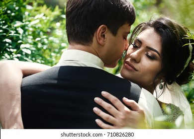 Greenery Surrounds Wedding Couple Hugging In The Garden