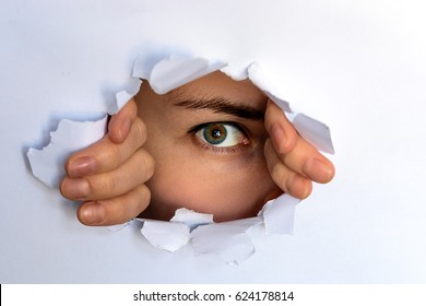 the green-eyed girl looking through torn paper. spying, glancing