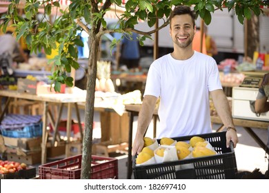 Greengrocer Owner Of A Small Business At An Open Street Market, Selling Organic Fruits And Vegetables, Carrying A Box Full Of Papaya.