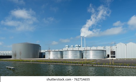 Greenhouse With Infront One Big And Three Small  Storage Tank Along A Canal