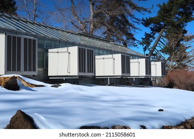 A Greenhouse On A Snowy Winter Day. Evaporative Swamp Cooler Temperature Control Units Mounted Outside The House.