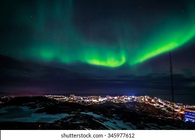 Greenlandic Northern Lights And Starlight Sky Over Highlighted Nuuk City View From Top Of Rocky Hill, Greenland