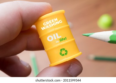 Greenwashing Concept. Man Paints A Barrel Of Oil With A Green Pencil. Greenwashing Is A Communication Technique Aimed At Building A False Image Of A Company In Terms Of Environmental 