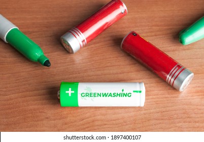 Greenwashing Concept: Some Batteries And A Green Marker On A Wooden Table. Greenwashing Is A Communication Technique Aimed At Building A False Image Of A Company In Terms Of Environmental 