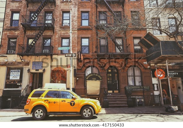 Greenwich village, New York City - April 21, 2016 : A\
yellow taxi in Greenwich Village parked in front of old resident\
