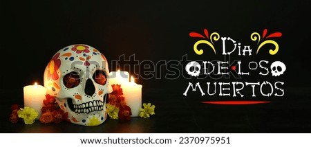 Greeting banner for Mexico's Day of the Dead (El Dia de Muertos) with painted human skull, candles and flowers