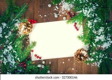 greeting card for the Christmas holidays . Spruce branches , cones and red berries covered with snow . Space for labels on a wooden surface . - Powered by Shutterstock