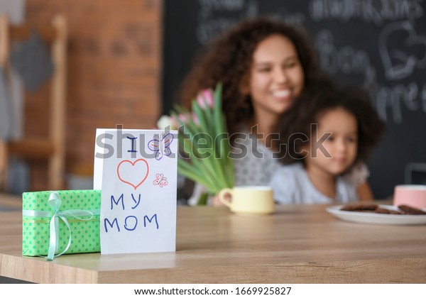 Greeting card and gift for Mother\'s Day on table\
in kitchen