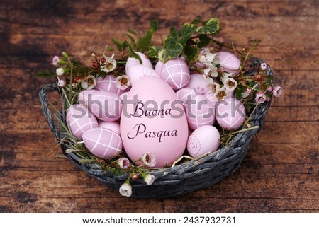 Greeting card Happy Easter: Inscribed Easter egg with Easter eggs and flowers in a nest. Italian inscription translates as Happy Easter.