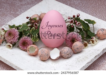 Greeting card Happy Easter: Inscribed Easter egg with quail eggs and flowers. French inscription translates as Happy Easter.