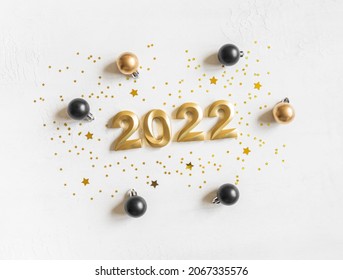 Greeting card - happy new year with numbers 2022, gold glitter and christmas balls on white textured background. Minimal holiday concept. Top view. Flat lay - Shutterstock ID 2067335576
