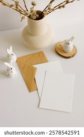Greeting Card mockup, envelope ,Easter funny bunny eggs decor ,spring willow branches in a vase in neutral colors on white  backdrop top view flatlay. Copy space.Aesthetic Easter background.