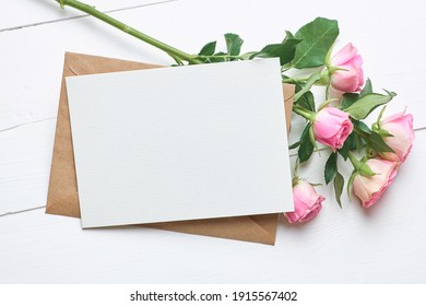 Greeting Card Mockup With Fresh Roses On White Wooden Background, Top View, Copy Space