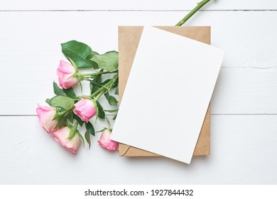 Greeting Card Mockup With Fresh Roses On White Wooden Background, Top View, Copy Space