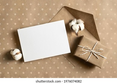 Greeting Card Mockup With Gift Box, Envelope And Cotton Flower On Craft Paper Background, Top View, Copy Space