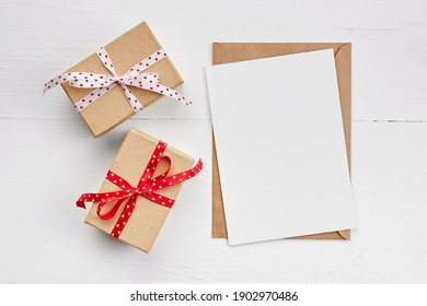 Greeting Card Mockup And Gift Boxes On White Wooden Background, Top View, Copy Space, Valentines Day